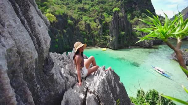 Mujer joven con sombrero de sol sentada en rocas de piedra caliza — Vídeos de Stock
