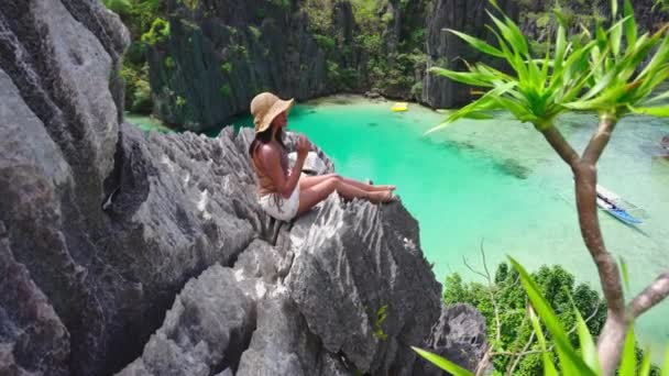 Vrouw in de zon hoed zittend op rotsen boven verborgen strand — Stockvideo