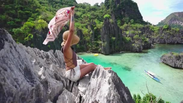 Женщина, держащая шаль в бризе на известняковых скалах — стоковое видео