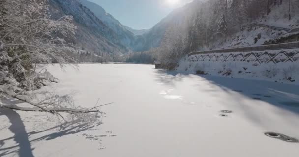 Drohne über gefrorenem Klammsee im Tal bei gleißendem Sonnenlicht — Stockvideo