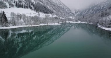 Klammsee Gölü üzerindeki insansız hava aracı Karla kaplı ağaçlarla çevrili