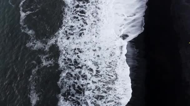 Drohnen-Blick auf weiße Flut am schwarzen Sandstrand — Stockvideo