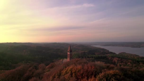 Κηφήνας πάνω από το δάσος με πύργο και λίμνη στο ηλιοβασίλεμα — Αρχείο Βίντεο
