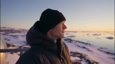 Ilulissat Icefjord, Grönland 'da gün batımına bakan Tüylü Şapkalı Olgun Adamın Orta Yavaş Hareketli Çekimi