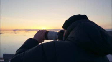 Ilulissat Icefjord, Grönland 'da günbatımını çekmek için kameranın uzun lenslerini odaklayan Yavaş Çekime Yakınlaş