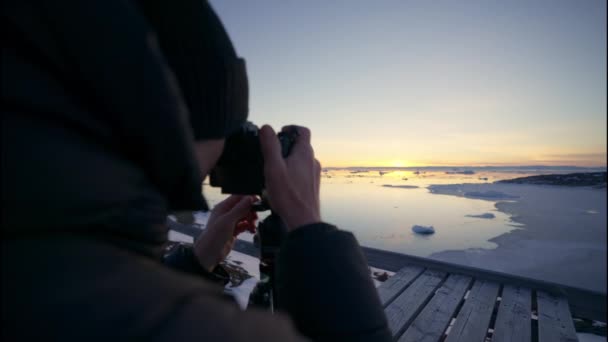 スロー モーション メディア アーキング ラック フォーカス ショット イリュリサットの海に沈む夕日に焦点を当てた男性写真家 Icefjord Greenland — ストック動画