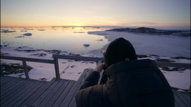 Medium Arcing Shot Photographer Adjusting Camera Tripod Shoot Sunset Ilulissat — стокове відео