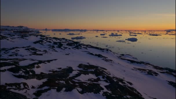 グリーンランドの日没時にイルリサットの氷と雪の上でワイドパンニングショット — ストック動画