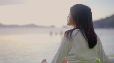 Koyu saçlı bir kadının portresi lüks bir oteldeki Sonsuz Yüzme Havuzu 'nun Önünde Gelen Günbatımının tadını çıkarıyor. Sakinleştirici atmosfer. Yavaş Hareket Görüntüsü