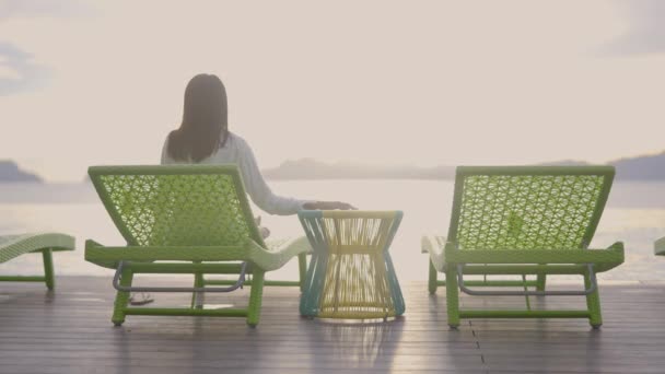Kobieta Ciemnymi Włosami Siedząca Zielonym Leżaku Ciesząca Się Widokiem Nadchodzącego — Wideo stockowe