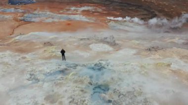 Bir Erkek Turistin Hava Destanı Çekimi, Myvatn Gölü yakınlarındaki Hver Jeotermal Bölgesi 'nin tadını çıkarıyor. Geniş açılı panoramik çekim. Kamera Yavaşça Uzaklaşıyor
