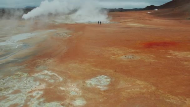 2人の観光客の空中撮影Myvatn湖の近くのHverir地熱地域の蒸しフマロールを見てください パノラマワイドショット カメラがゆっくりとズームイン — ストック動画