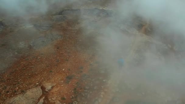 Myvatn湖の近くの蒸しハーバー地熱地帯の空中ビュー アイスランド パノラマワイドショット 男の観光客が歩き回る 角度の高いショット ドローンは観光客を追いかけ 蒸気を飛び越える — ストック動画