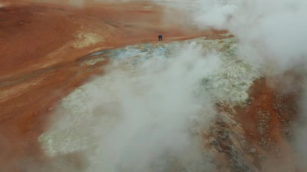 Zdjęcie Lotnicze Dwóch Turystów Stojących Przed Parującą Fumaroles Obszarze Geotermalnym — Wideo stockowe