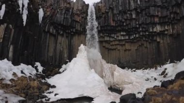 Svartifoss Şelalesi ve bazalt lav sütunları destansı manzarası. Vatnajokull Ulusal Parkı, İzlanda. Kamerayla Yavaş Çekim Yakınlaştır. Buza Düşen Su Akıyor.