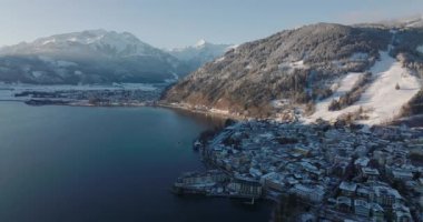 Geniş İHA Zell Gölü 'nün üzerinden geri çekiliyor. Kasabanın gölgesinde güneşli karlı dağlar, Zell Am See-Kaprun, Salzburg, Avusturya
