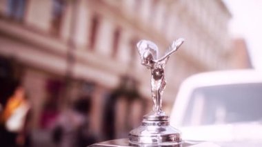 Araba Kaputuna Rolls Royce Amblemi 'nin Yavaş Çekim Bokeh Çekimi. Bulanık Arkaplanda Sürücü Arabanın Kapısını Açar