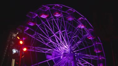 Gece vakti lunaparkta dönen dönme dolabı aydınlatmış. Aşağıdan Görünüm