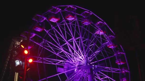 启明的摩天轮在夜晚的游乐园中旋转 自下而上的视图 — 图库视频影像