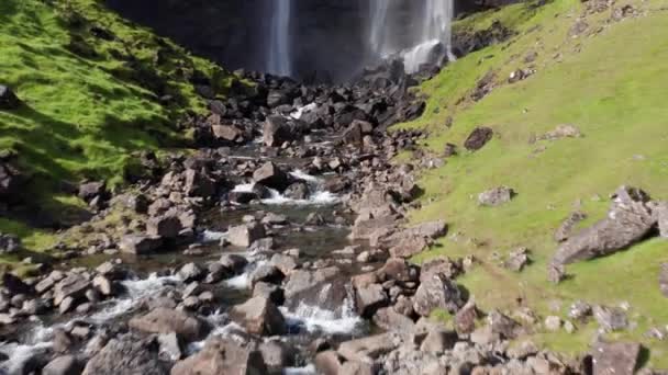 フェロー諸島の楽しいフォッサ滝の空中 ワイルドロッキーヒルサイドの雄大な滝 カメラが岩の上を後方に移動 — ストック動画