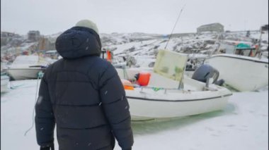 Grönland, Avannaata Belediyesi, Ilulissat 'ta karla kaplı bir tekneye doğru yürürken çekilen yavaş çekim görüntüsü.