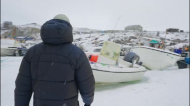Grönland, Avannaata Belediyesi, Ilulissat 'ta karla kaplı bir tekneye doğru yürürken çekilen yavaş çekim görüntüsü.