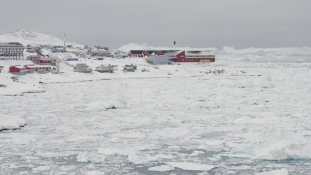 雪に覆われた建物に氷の上に広いズームアウト Avannaata自治体 グリーンランドのIlulissatの町 — ストック動画