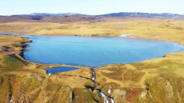 İzlanda 'nın Altın Tarlaları ile çevrili küçük mavi bir gölün havası. Panoramik çekim. Kamera Geriye Taşır