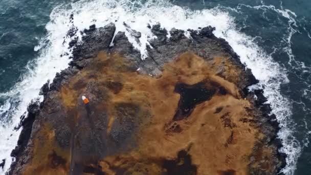 空中の海の波アイスランドの海岸にあるロッキークリフに衝突します トップダウンショット カメラがダウンし ドローンが着陸 — ストック動画