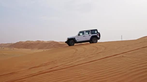 ドバイの砂漠を走る白いジープの広いスローモーショントラッキングショット — ストック動画