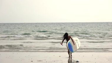 Ağır çekimde, elinde raket ve Tayland Denizi 'ne Oar taşıyan kadının görüntüsü.
