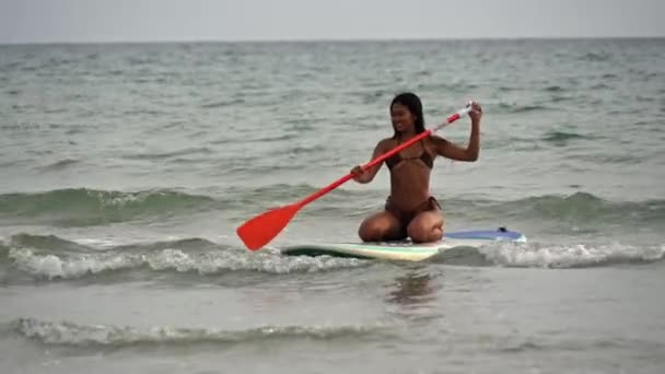 Wide Shot Young Woman Bikini Kneeling Paddleboard Rowing Oar Sea — стокове відео