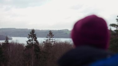 Büyük sırt çantalı turist, Danimarka 'nın Himmelbjerget bölgesindeki bir gözlem noktasından göl manzarasının keyfini çıkarıyor. Odaklanma arka planda. Döndürme Çekimi