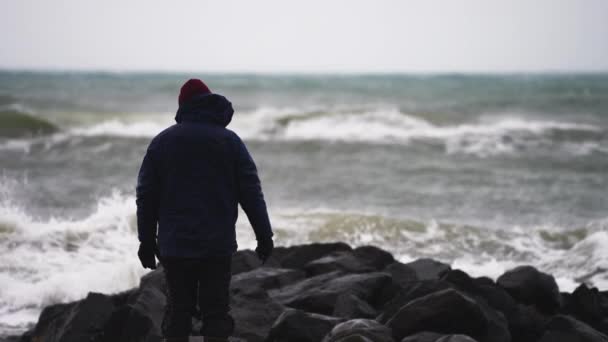 Kışlık Kıyafetli Adam Rocky Sahili Nde Deniz Kenarında Duruyor Gelen — Stok video
