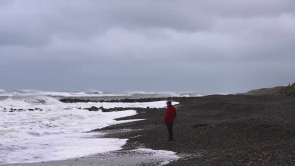 Człowiek Zimowych Ciuchach Spaceruje Nad Morzem Skalistym Wybrzeżu Ogląda Nadchodzącą — Wideo stockowe