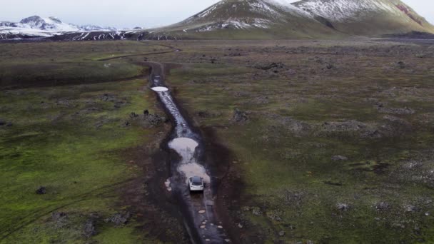 Aerial Car Driving Puddle Mud Dirt Road Majestic Snow Capped — Stockvideo