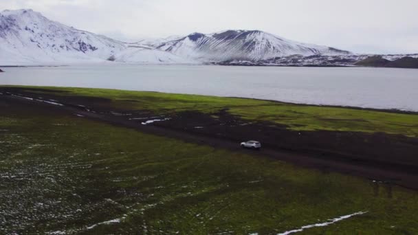 호숫가를 진흙투성이의 자동차를 아이슬란드 지대에 산들을 수있다 파노라마 추적하는 카메라 — 비디오