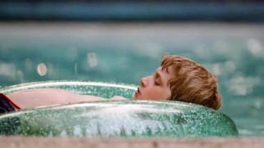Close-up Portrait of a Boy Laying on an Inflatable Circle and Floating in the Pool on Summer Vacation. Slow Motion Shot