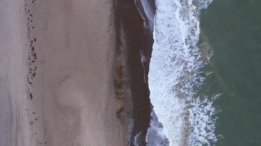 Aerial Over a Sandy Coastline. Waves Are Crashing to the Shore. Beautiful Seascape.Top Down Shot. Camera Moves Forwards