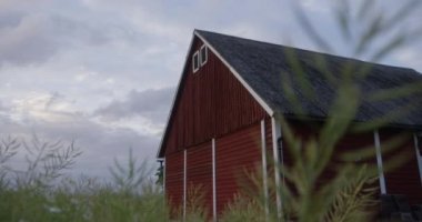 Low Angle Handheld Arcing Shot Of Red, Wooden Barn In Field At Dusk