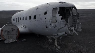 İzlanda 'da Black Sand Beach Solheimasandur' da terk edilmiş bir uçağın hava yoluyla yakın plan çekimi. Kamera yukarı doğru hareket ediyor. Drone Enkazın Önünde Kalkıyor