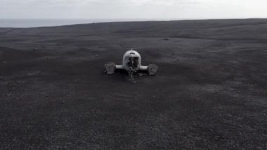İzlanda 'daki Kara Kum Sahili Solheimasandur' da terk edilmiş bir uçağın enkazı. Kamera ileri doğru hareket ediyor. İnsansız Hava Aracı Enkazın Üzerinde Uçuyor