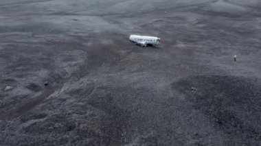 İzlanda 'daki Kara Kum Sahili Solheimasandur' da terk edilmiş bir uçağın enkazı. Kamera ileri doğru hareket ediyor. İnsansız hava aracı enkazın üzerinde uçuyor. Geniş Panoramik Görüntü