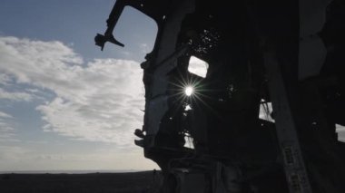Silhouette of Crashed Plane Fuselage Against the Sun on Solheimasandur Beach, Iceland. Sun Rays Break Through the Hole in Fuselage. Bottom Up Shot