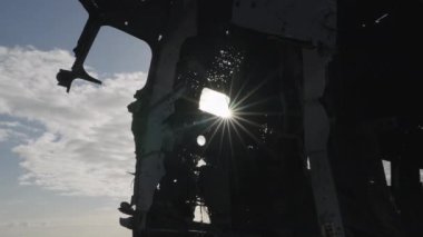 Silhouette of Crashed Plane Fuselage Against the Sun on Solheimasandur Beach, Iceland. Sun Rays Break Through the Window of Fuselage. Bottom Up Shot. Camera Zooms Out