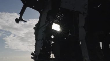 Silhouette of Crashed Plane Fuselage Against the Sun on Solheimasandur Beach, Iceland. Sun Rays Break Through the Window of Fuselage. Bottom Up Shot. Camera Zooms Out