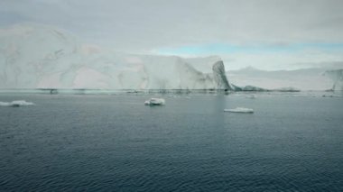 Wide Tracking Shot From Boat Over Sea Following Flock Of Birds Flying By Iceberg, Greenland