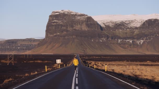Man Yellow Jacket Running Empty Asphalt Road Front Majestic Mountains — Vídeo de Stock
