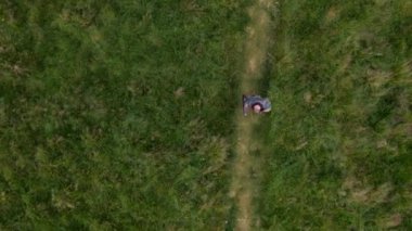 Yeşil Çayır 'da Yol Boyunca Yürüyen Bir Adam' ın Havadan Aşağı Görünümü. Kamera adamı takip ediyor.