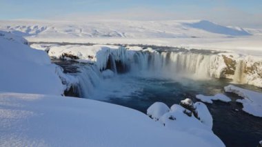 lockdown wide shot of sunlit godafoss waterfall and Skjalfandafljot river with snow and ice, iceland